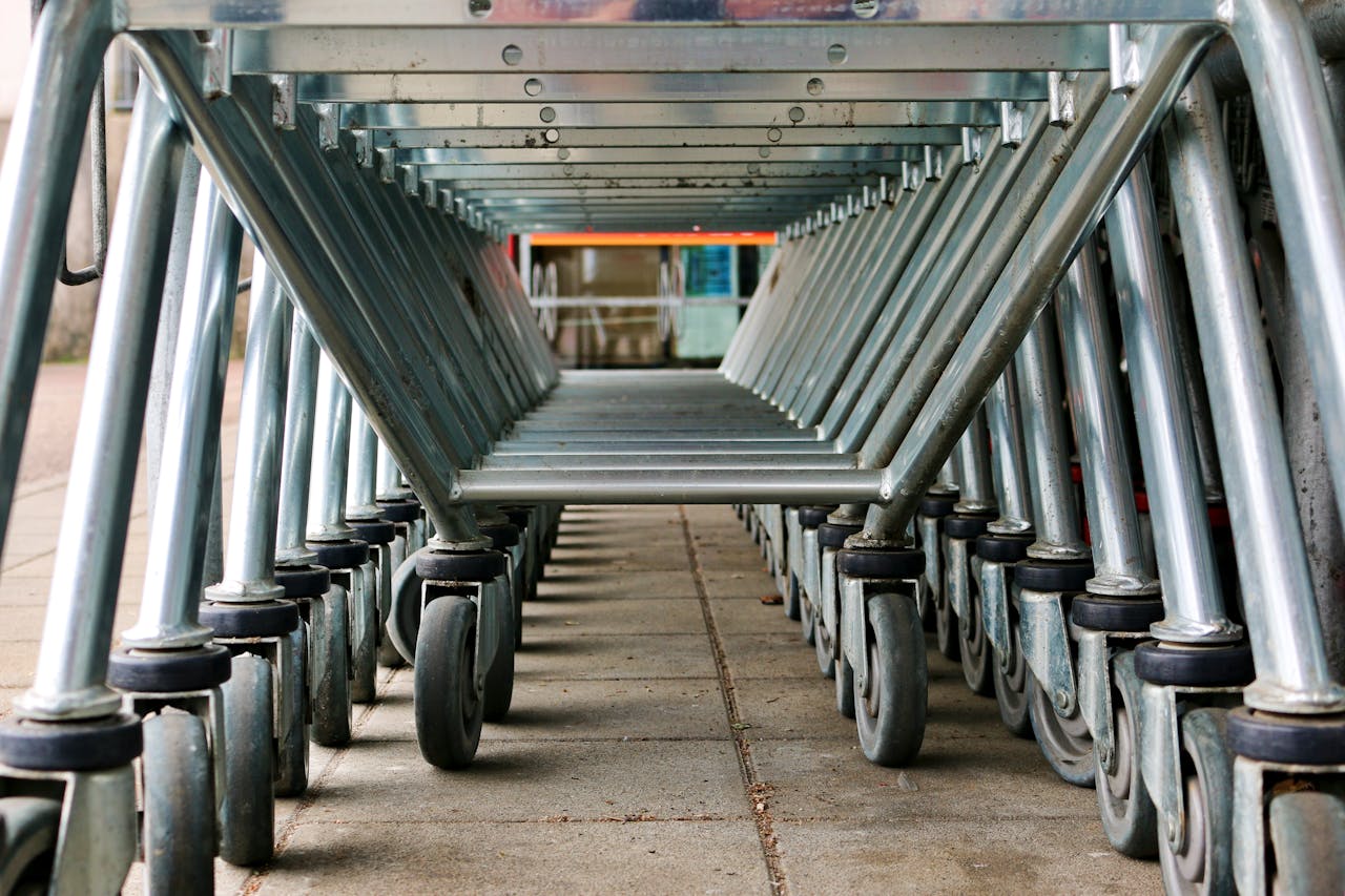 A low-angle view of a row of metal shopping carts on concrete pavement in Ulm, Germany.
